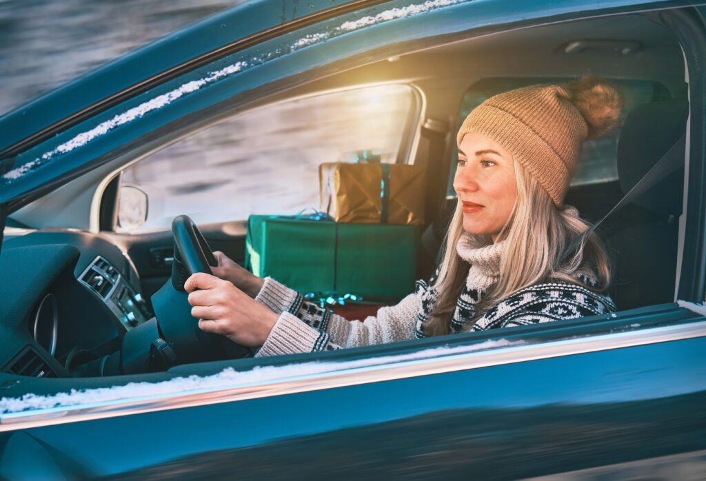 woman driving a blue car with presents in her passenger seat